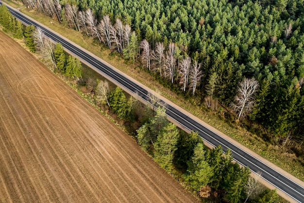 Road along the forest and field top view from a drone