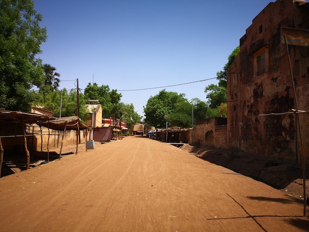 Road amidst buildings against clear blue sky