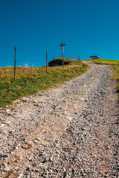 Road amidst field against clear blue sky