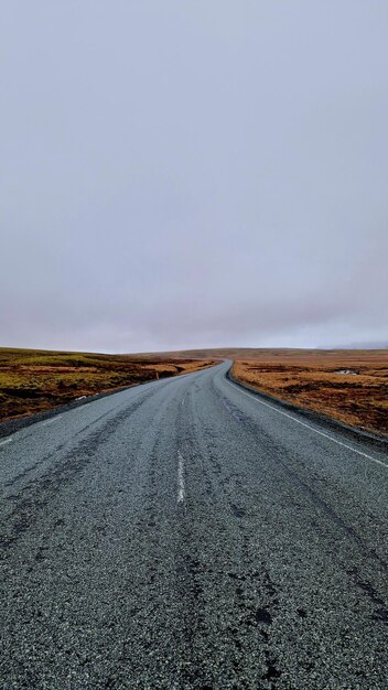 Foto strada in mezzo al campo contro un cielo limpido