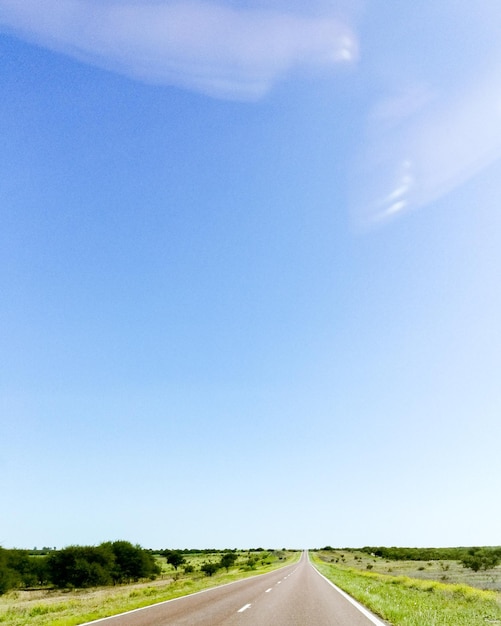 Road amidst field against clear sky