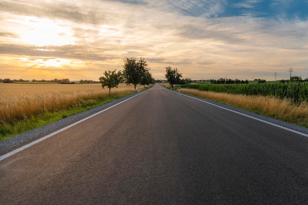 road amidst field against sky during sunset