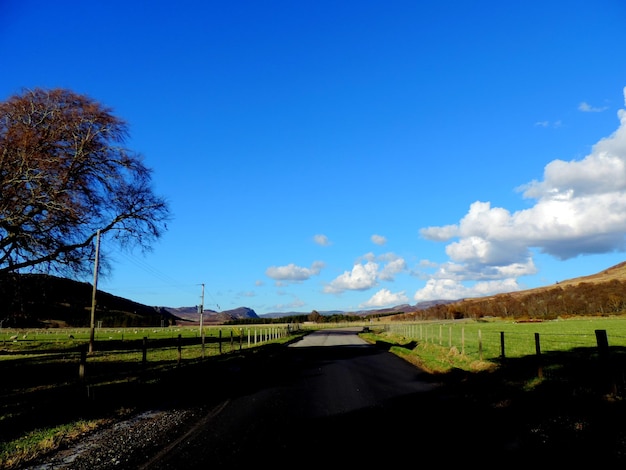 Road amidst field against sky