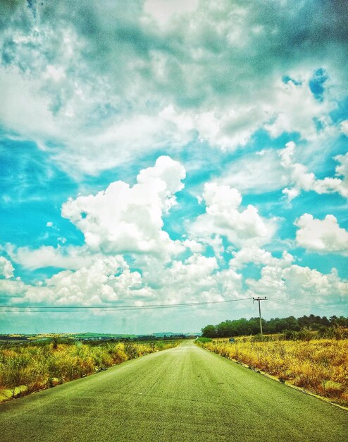 Road amidst field against sky