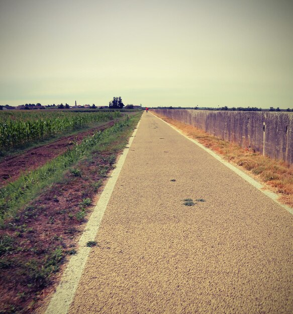 Road amidst field against sky