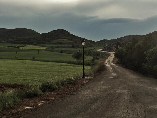 Road amidst field against sky