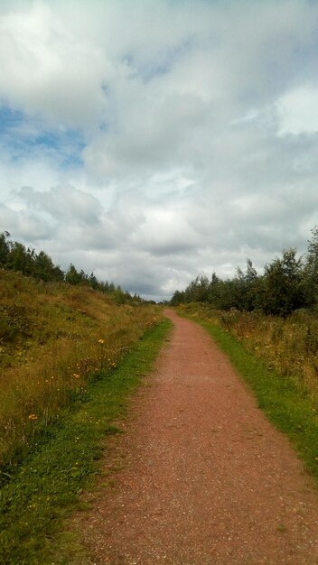 Road amidst field against sky