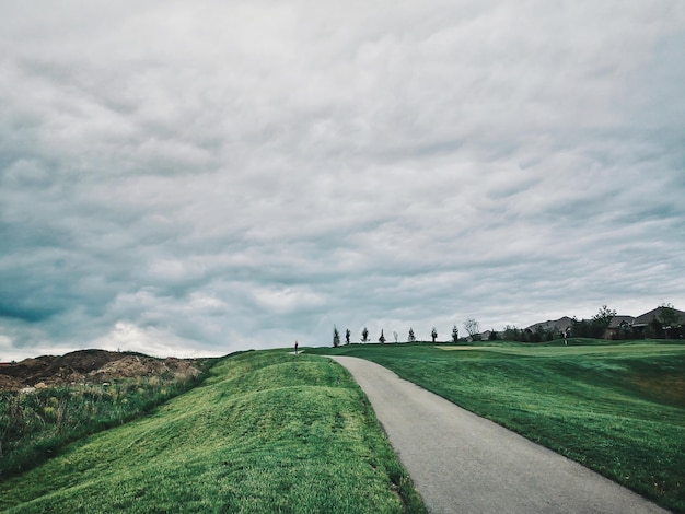 Road amidst field against sky