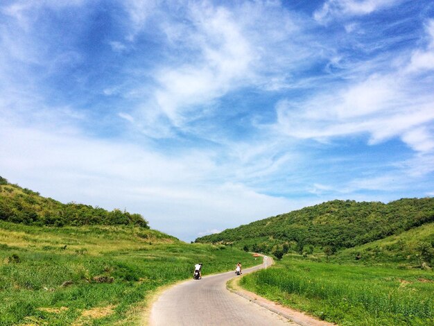 空に照らされた緑の風景の中の道路