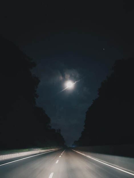 Foto strada in mezzo a una strada illuminata contro il cielo di notte