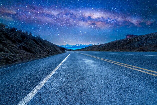 Photo road amidst landscape against sky at night