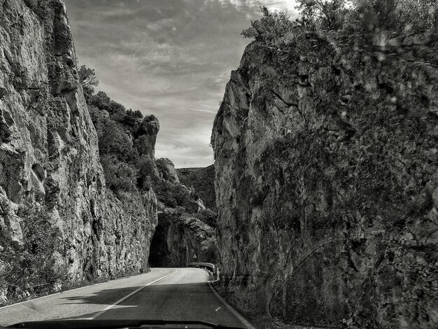 Foto strada in mezzo a formazioni rocciose vista attraverso il parabrezza dell'auto