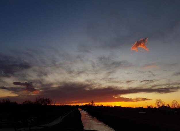 Photo road amidst silhouette trees against sky during sunset