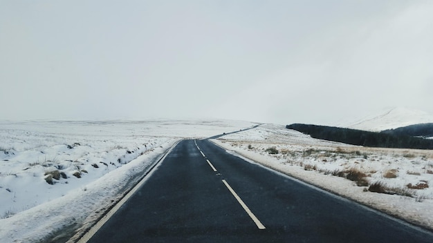 空に照らされた雪に覆われた畑の中の道路