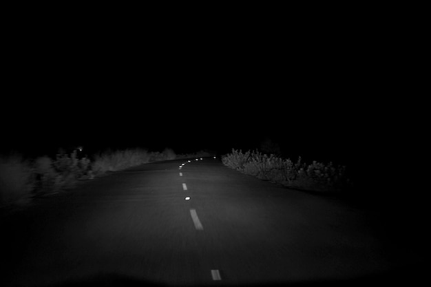 Photo road amidst trees against clear sky at night