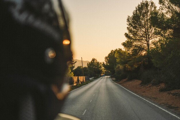 Photo road amidst trees against sky during sunset