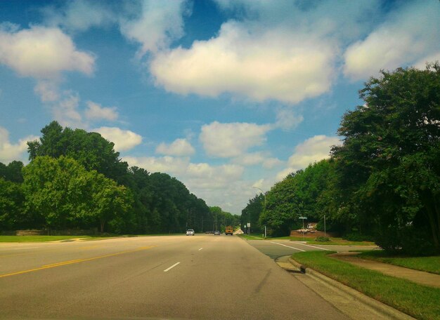 Photo road amidst trees against sky