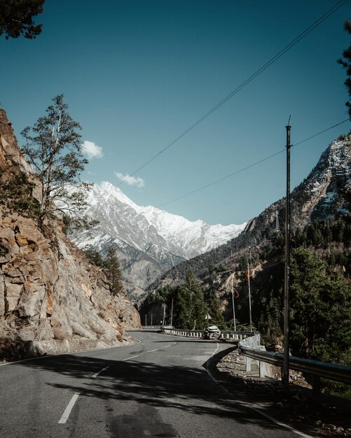 Photo road amidst trees and mountains against sky