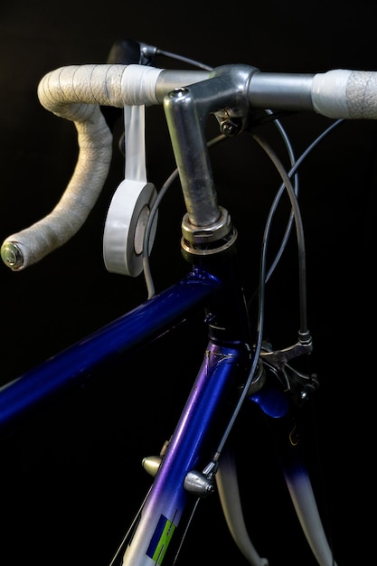 Road bike handlebars on a black background Install handlebar tape white Bicycle repair in a modern workshop Mechanic in the workshop hands and white insulating tape closeup