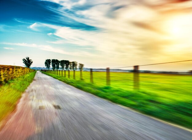 Road by agricultural field against sky