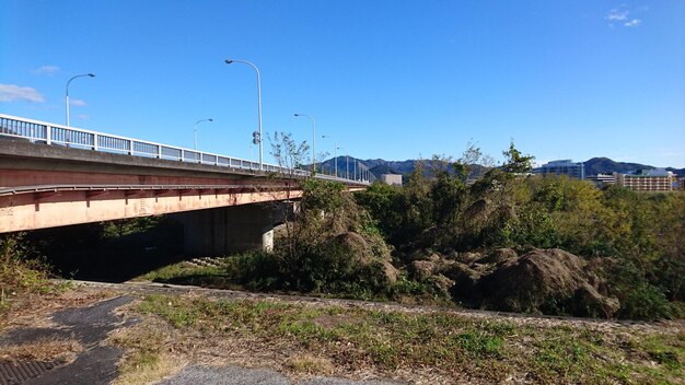 Road by bridge against clear blue sky