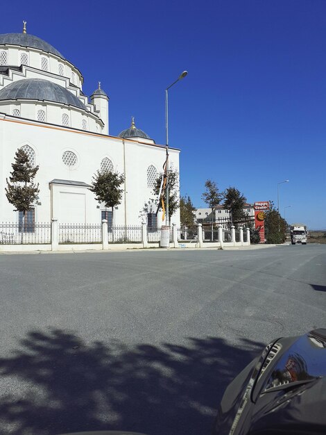 Road by building against clear blue sky