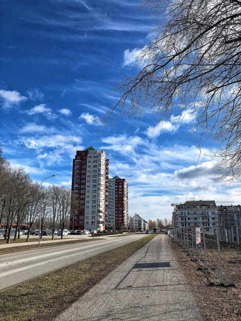 Road by buildings against sky in city