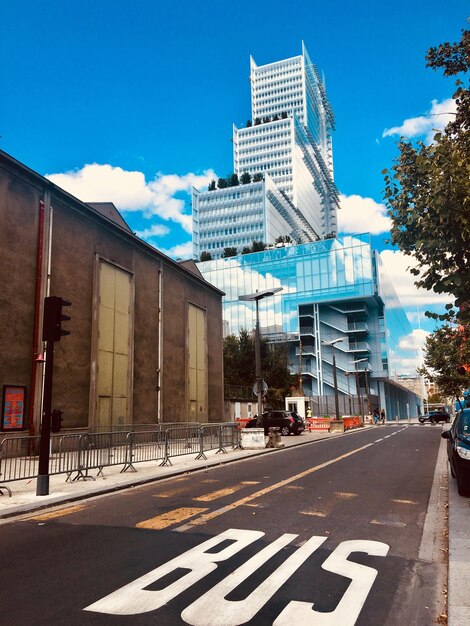 Road by buildings against sky in city