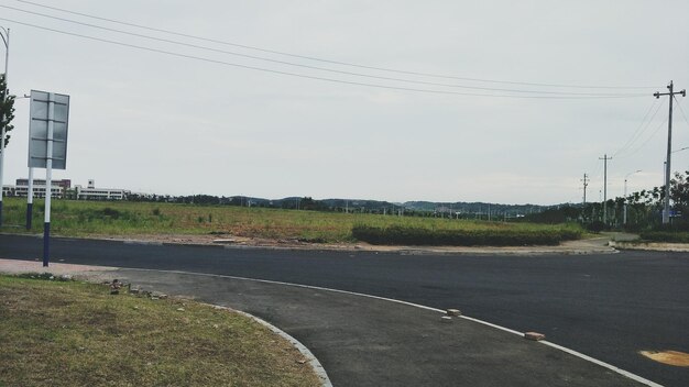 Road by field against sky