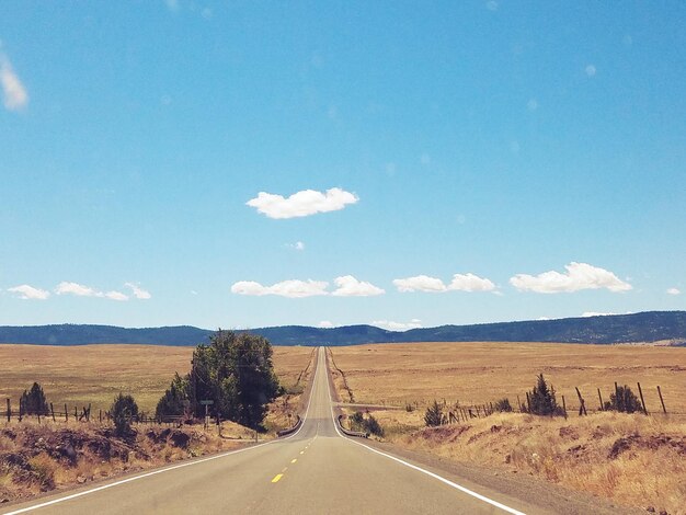 Road by landscape against blue sky