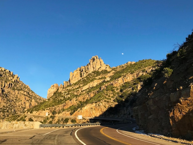 Road by mountain against clear blue sky