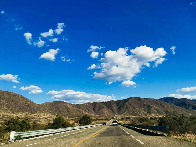 Road by mountains against blue sky