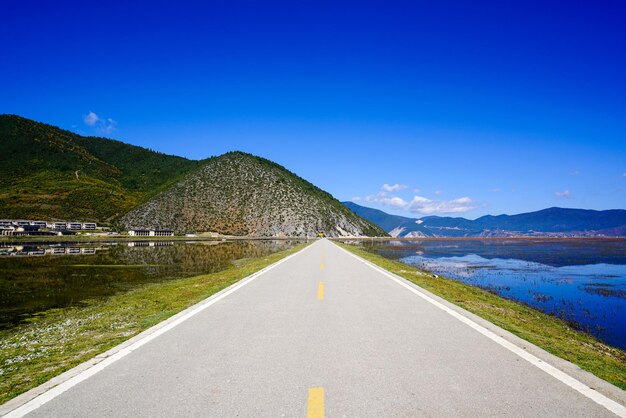 Road by mountains against clear blue sky