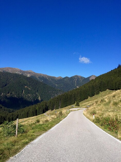 Road by mountains against clear blue sky