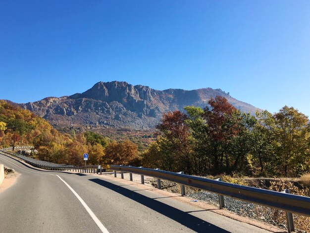 Road by mountains against clear blue sky