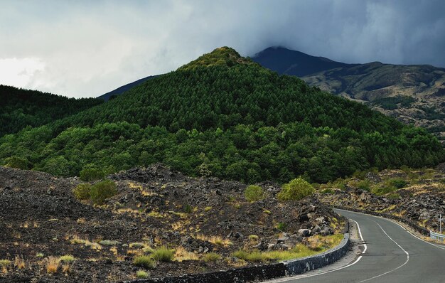 Road by mountains against cloudy sky