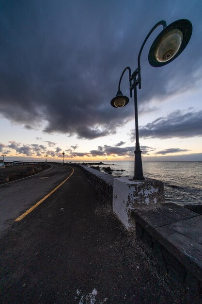 Photo road by sea against sky at sunset