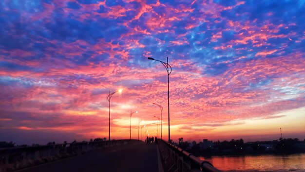 Road by silhouette bridge against sky during sunset