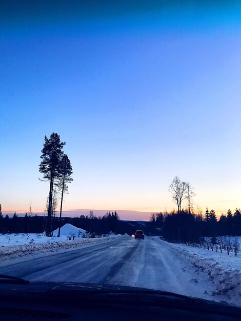 Road by silhouette landscape against clear blue sky during sunset