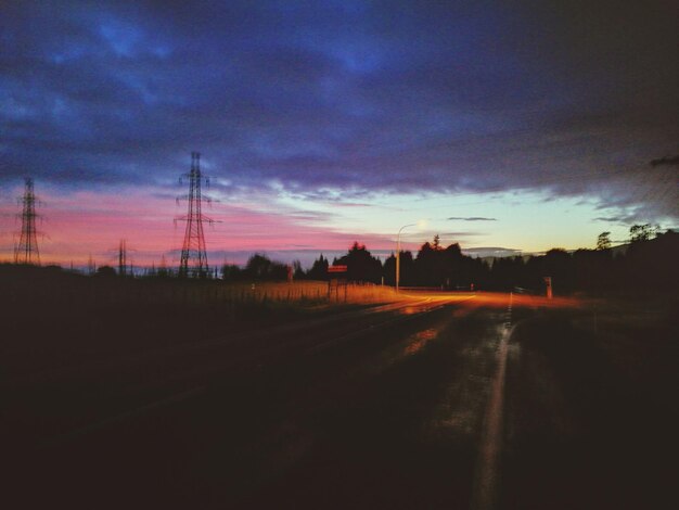 Road by silhouette landscape against dramatic sky during sunset