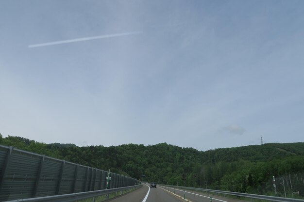 Road by trees against sky