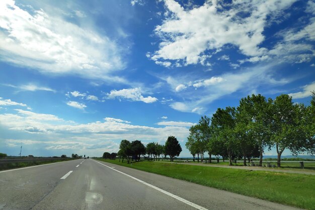 Road by trees against sky