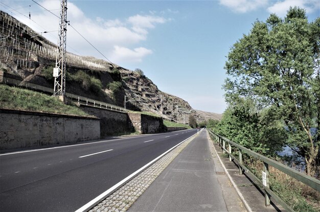 Foto strada tra gli alberi contro il cielo