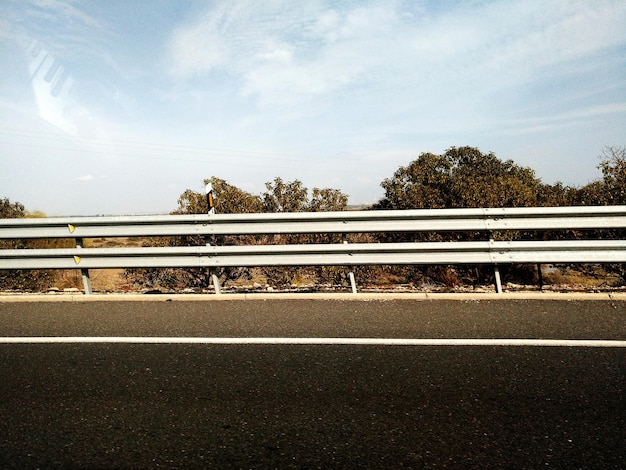 Foto strada tra gli alberi contro il cielo