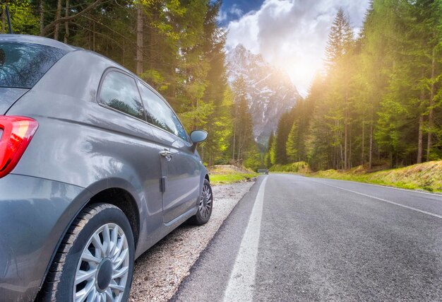 Road and car and Alpine mountains on the background May trip to South Tyrol in the Dolomites Northern Italy snow mountains sun flare as lens glare or toned