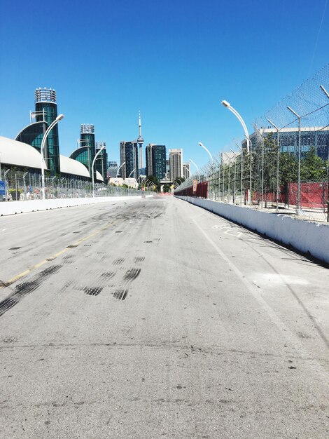 Road in city against clear blue sky