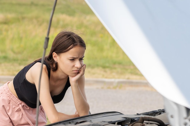 road helpwoman with a broken auto on the road is upset with an open hood waiting for assistance