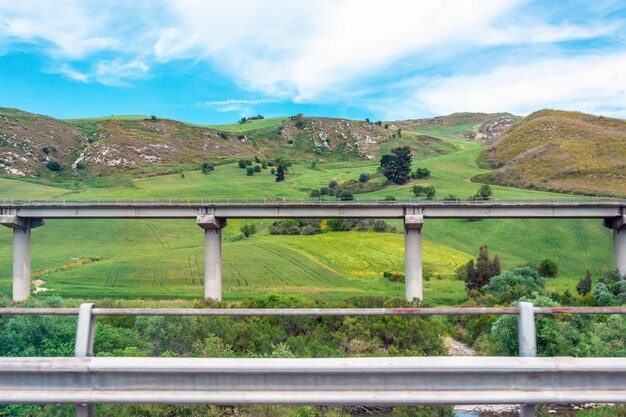 Road highway bridge viaduct supports in the valley among the green hills transport infrastructure