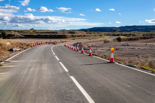 写真 予防措置のために円錐形でマークされた自然災害により荒廃した道路。建設中の道路。自然災害。