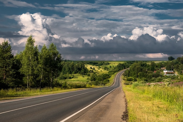 Foto la strada è tra la bellissima foresta e i campi in estate